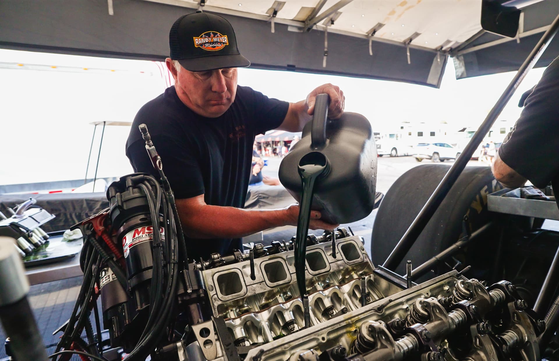 Randy Meyer pouring Maxima Racing Oil into a dragster engine