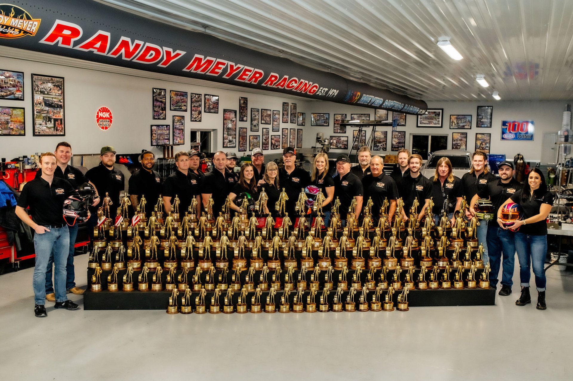 The Randy Meyer Racing crew posed in the shop with their collection of NHRA Wally trophies